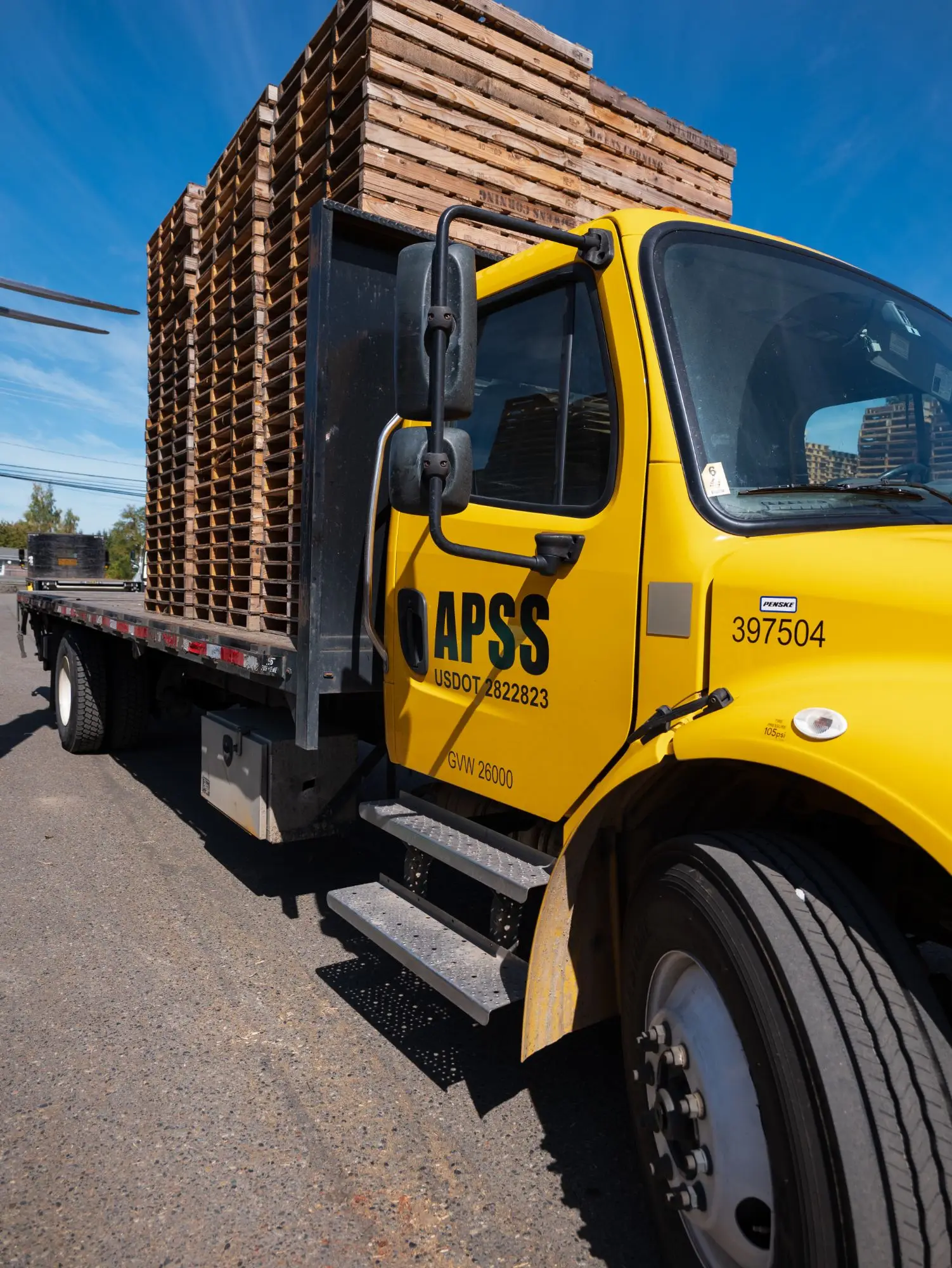 An APSS flatbed delivery truck loaded with wood pallets, ready to deliver across the Puget Sound